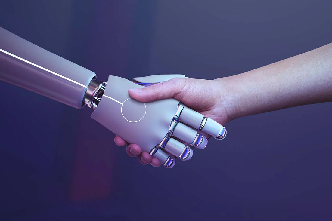 The image of a robot hand shaking hands with a person highlights the importance of human-machine collaboration in the face of how technology will change the future of work, what jobs will AI replace as well as what jobs are safe from AI